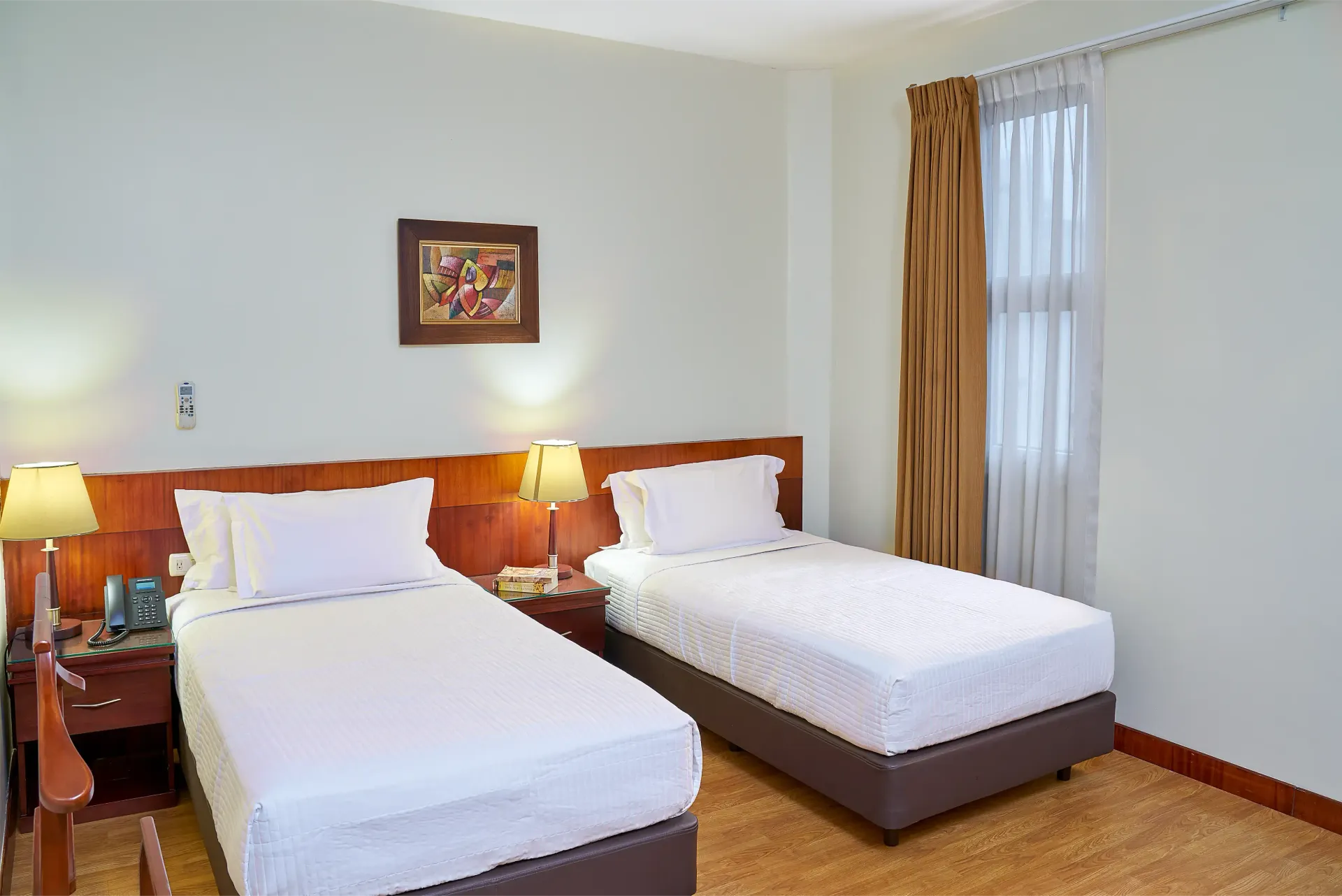 A hotel room with two beds and a window.