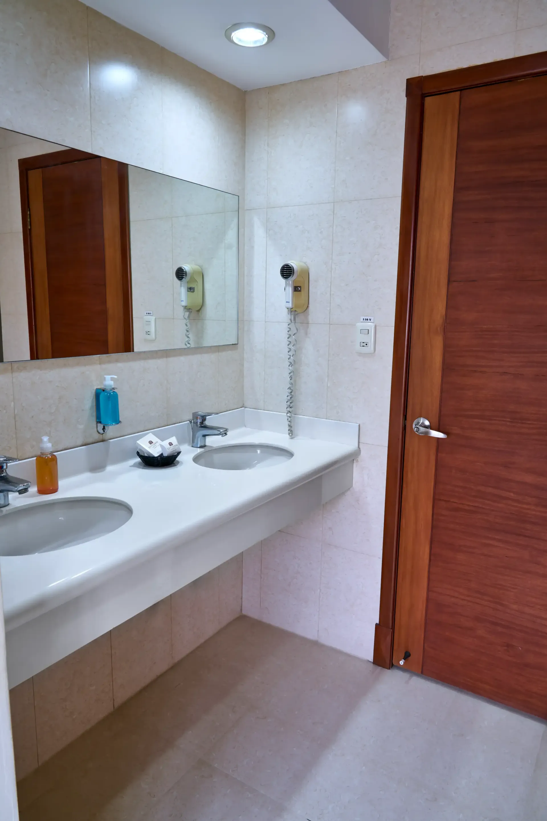 A bathroom with two sinks , a mirror and a door.
