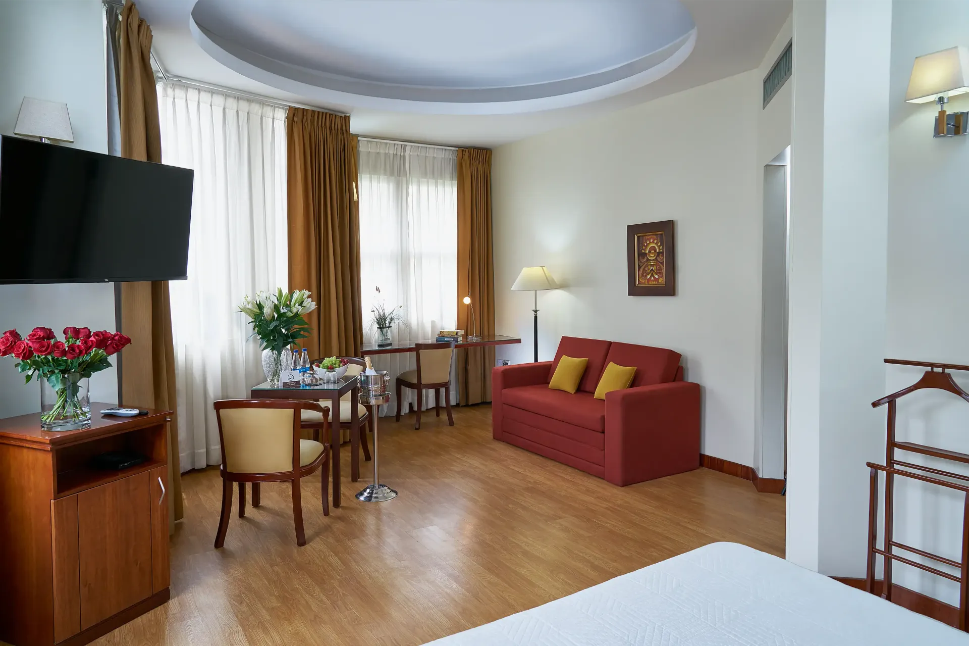 A hotel room with a bed , couch , chairs , table and television.