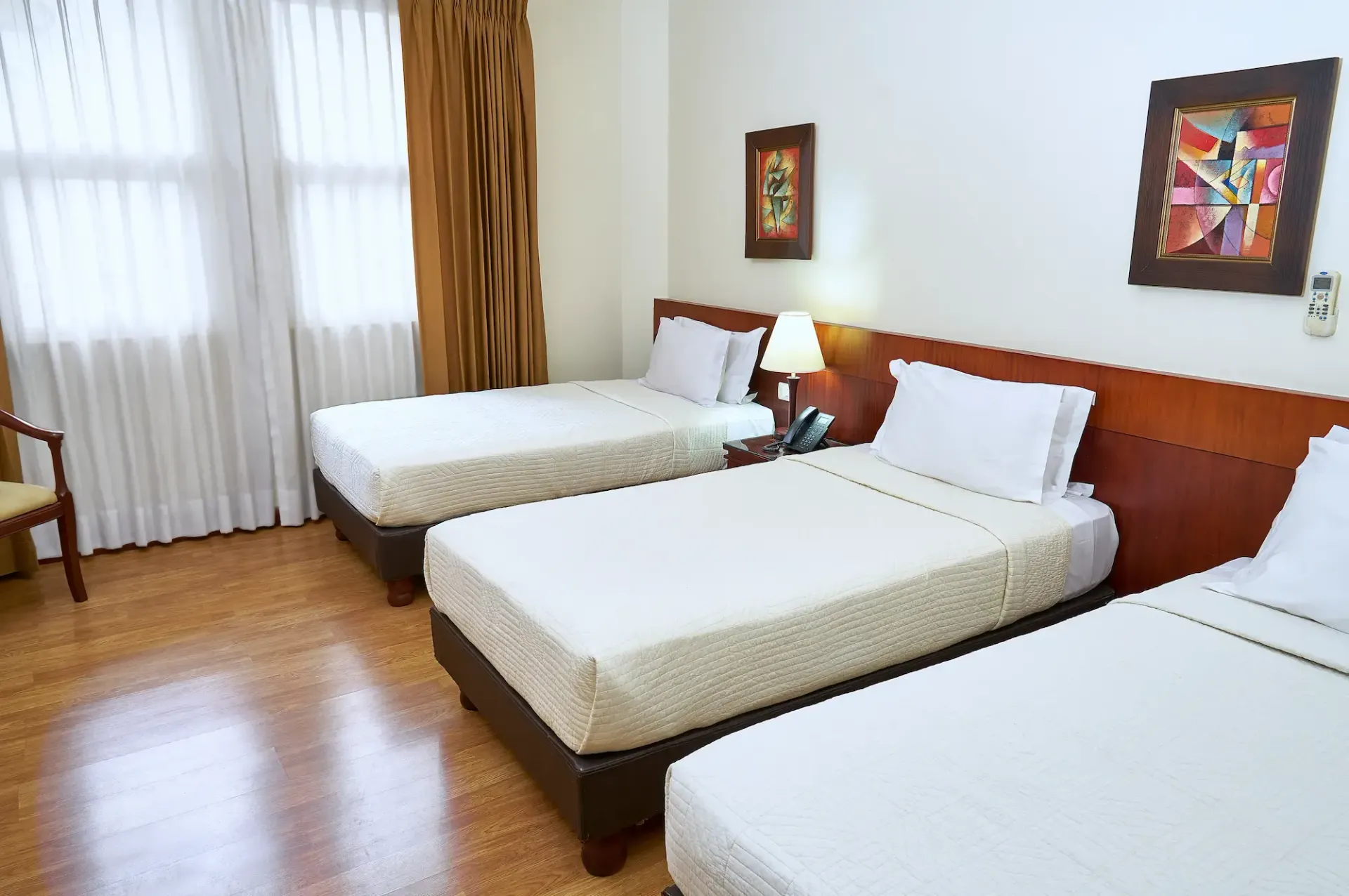 A hotel room with three beds and a chair