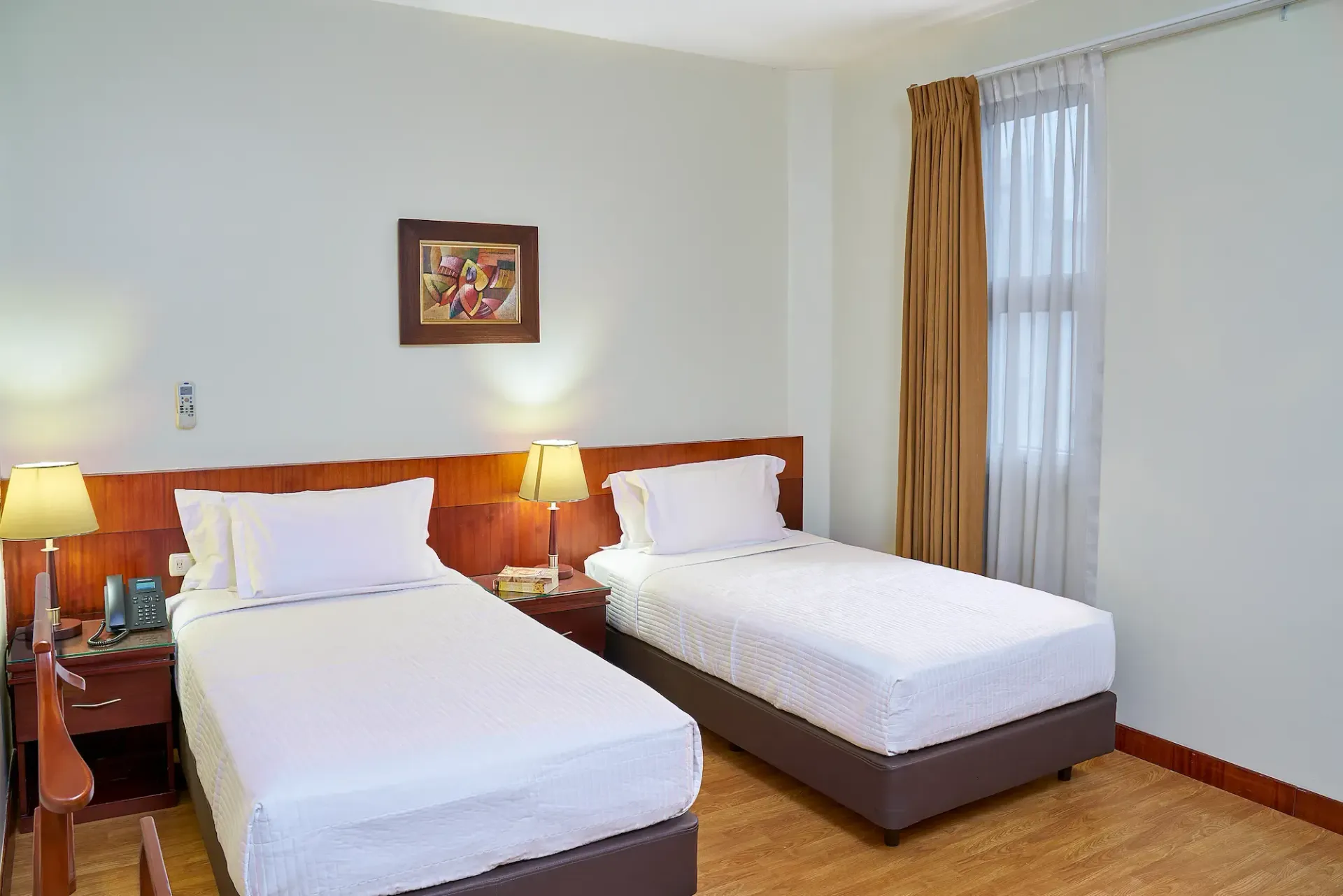 A hotel room with two beds and a window.
