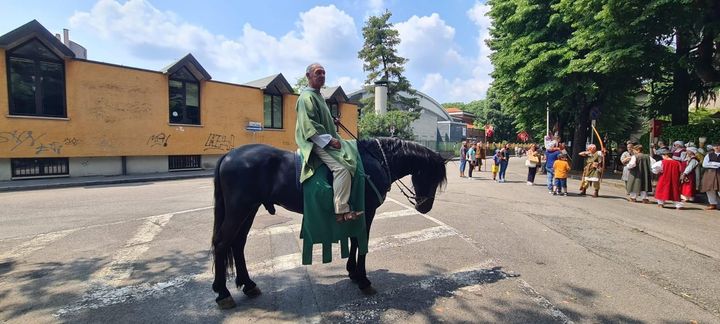 Due cavalieri a cavallo in un’arena sabbiosa, uno su un cavallo nero e l’altro su un cavallo bianco, con alberi sullo sfondo