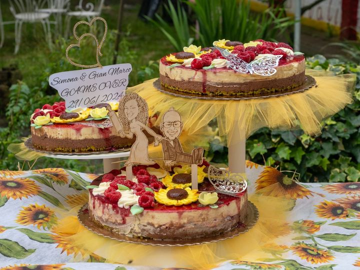 Allestimento decorativo per dolci all’aperto, con torte guarnite con frutti di bosco, girasoli e un cartello rustico con la scritta «welcome»