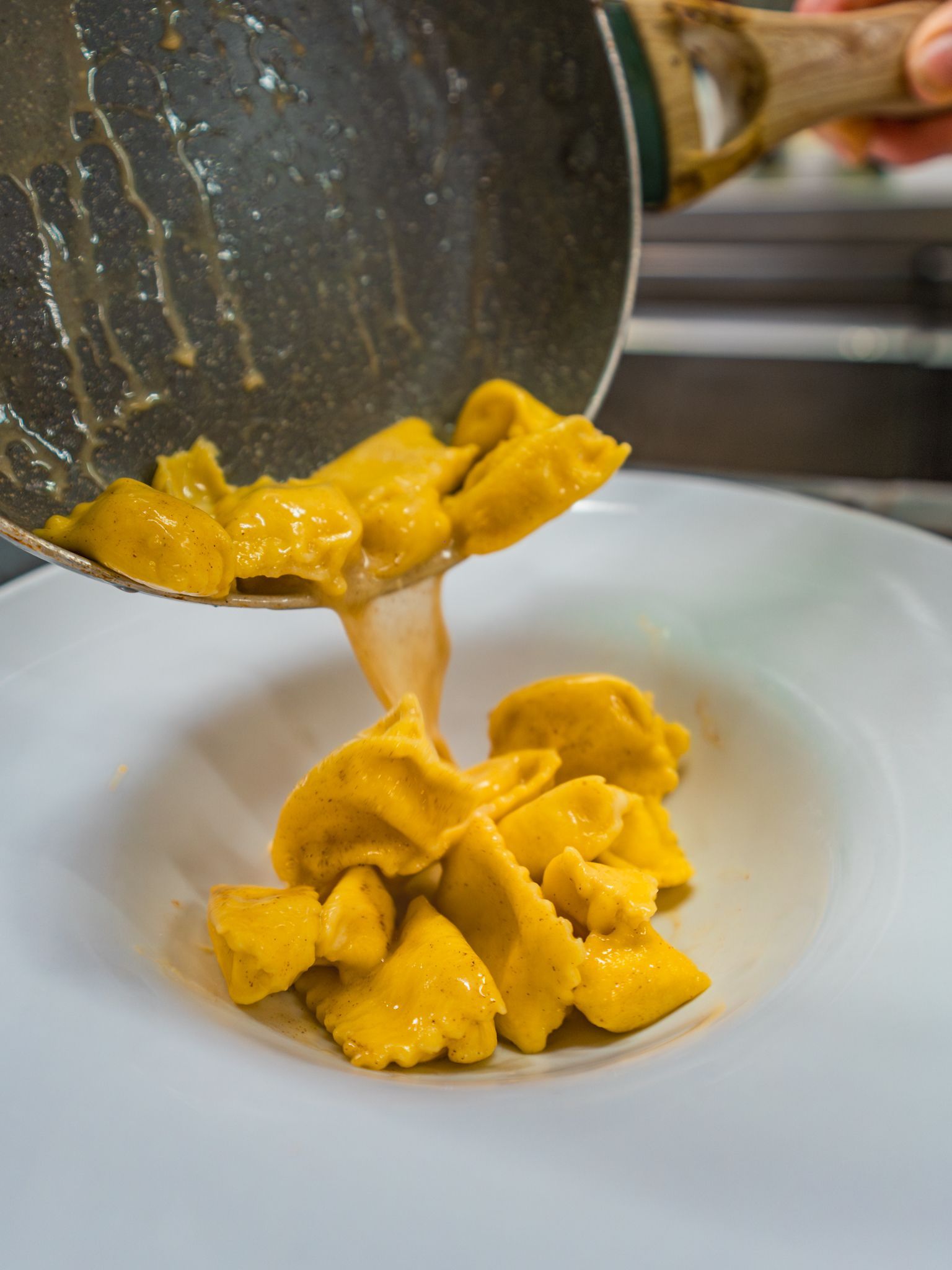 La pasta viene versata da una padella su un piatto bianco.