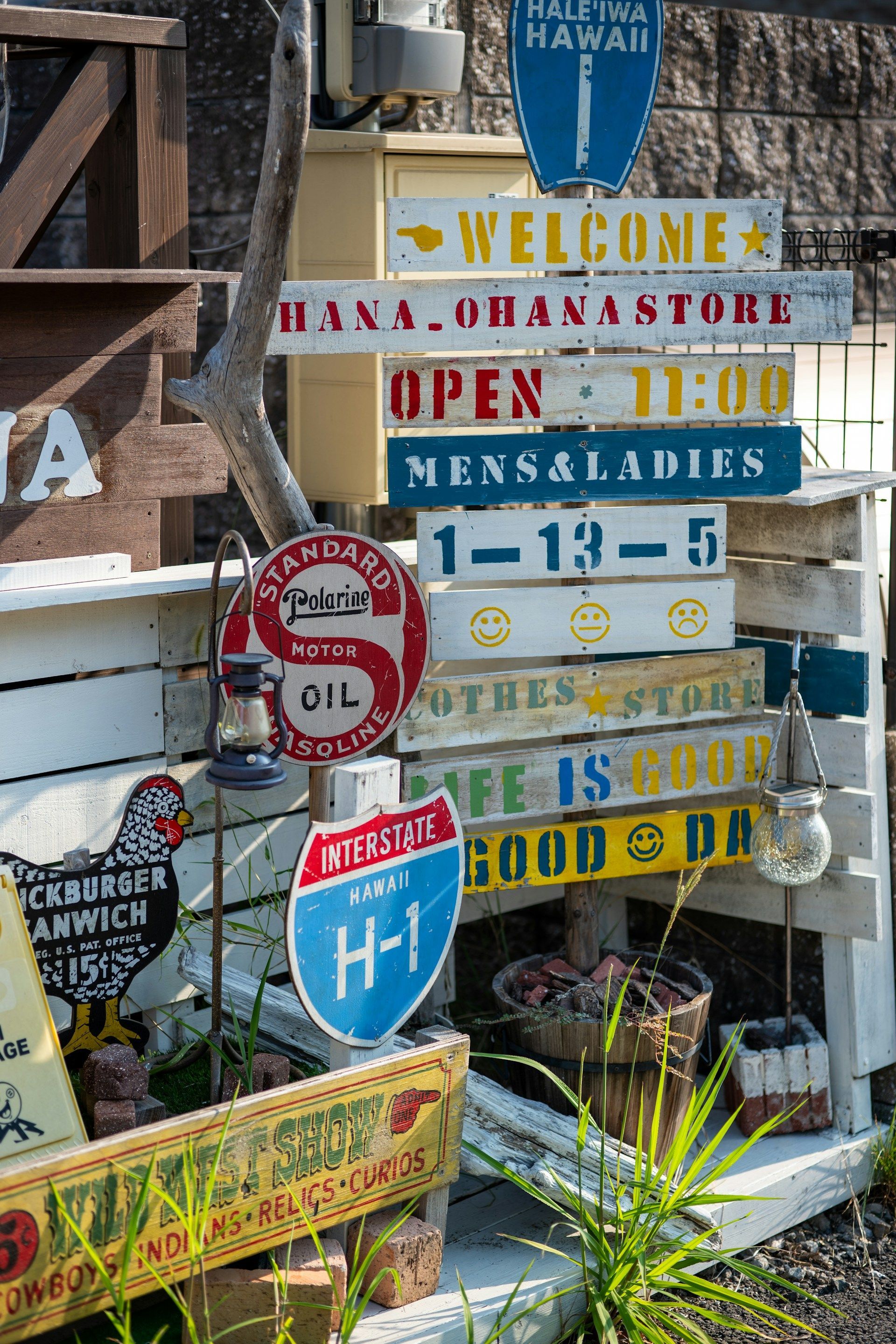 A bunch of signs are sitting on a wooden fence.