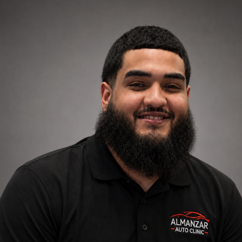 Smiling man in black shirt with Almanzar logo against a gray studio background