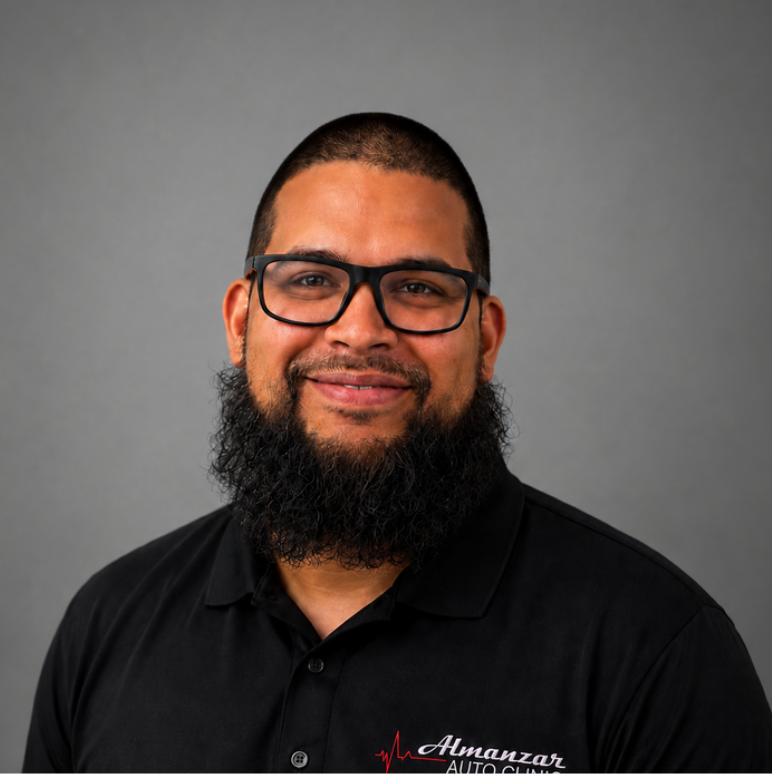 Smiling man with glasses and a beard in a black polo against a gray background