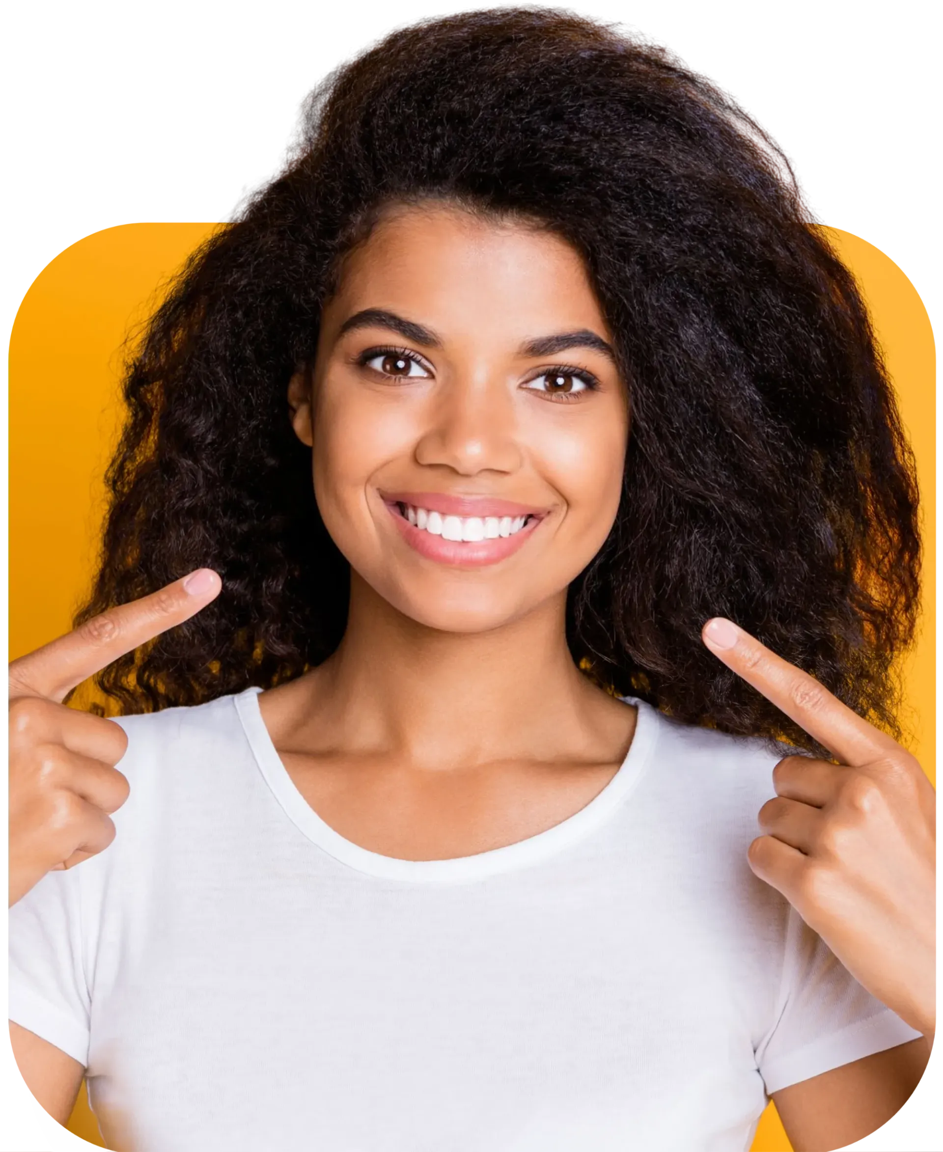 A woman with curly hair is smiling and pointing at her teeth.