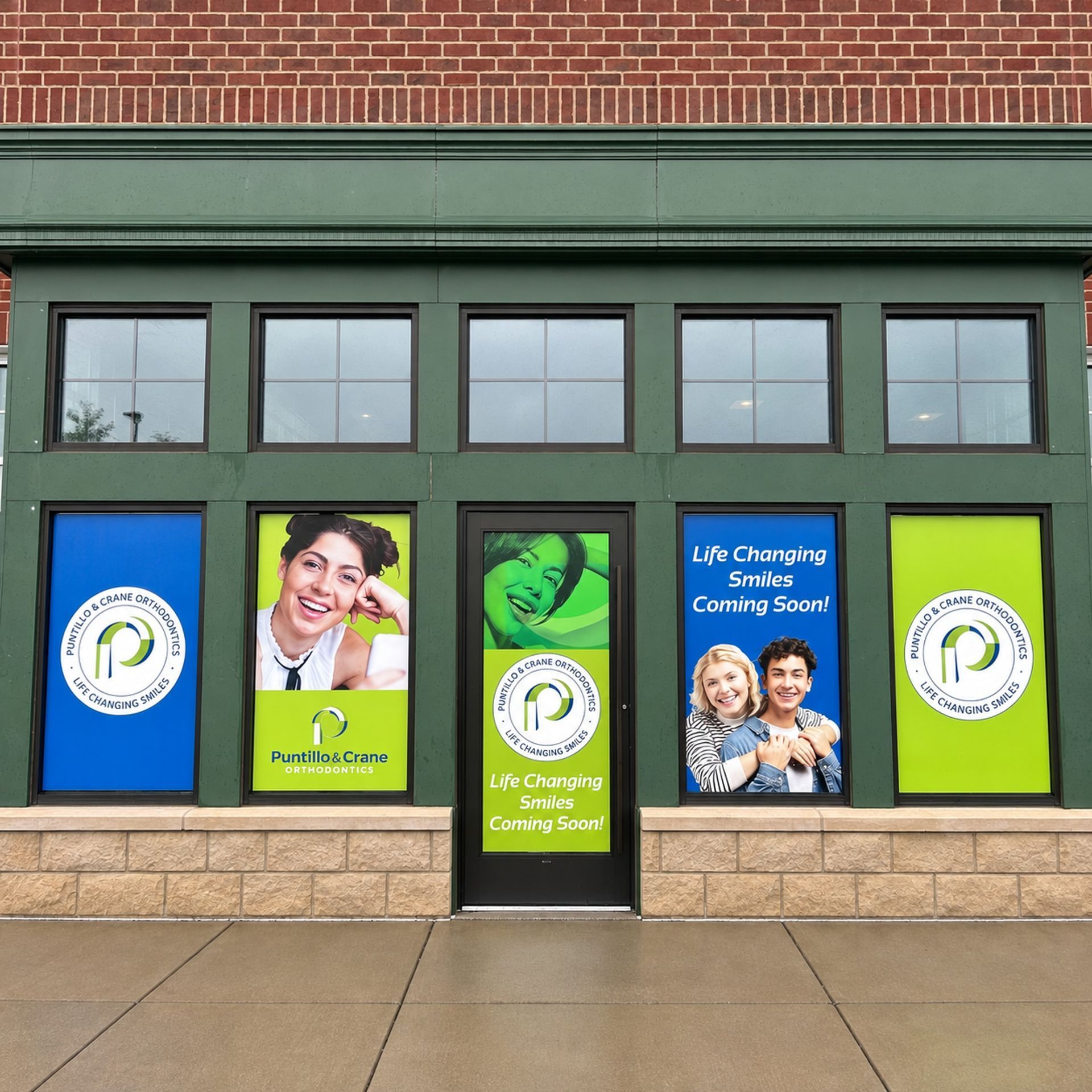 Storefront with green-framed windows and blue/green health clinic signs on a brick building.
