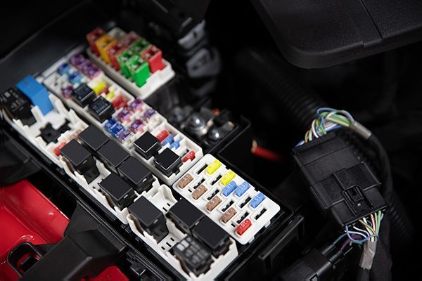Open car fuse box with colorful fuses and wiring. | Morin Brothers Automotive