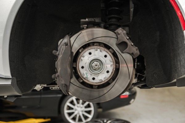 Car brake assembly with rotor, caliper, and suspension components, viewed up close. | Morin Brothers Automotive