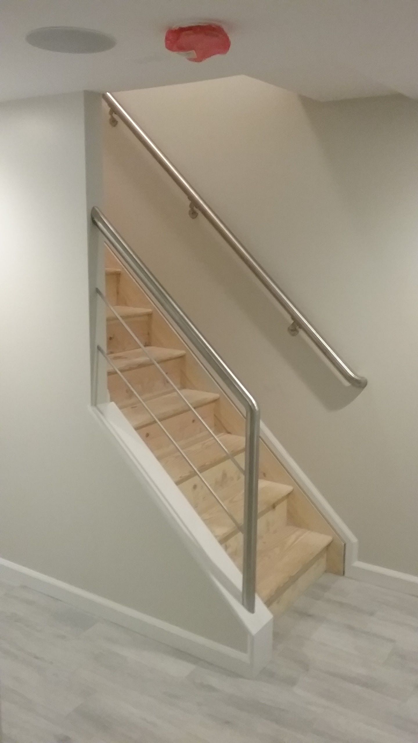 Indoor staircase with white walls, wooden steps, and a silver handrail.
