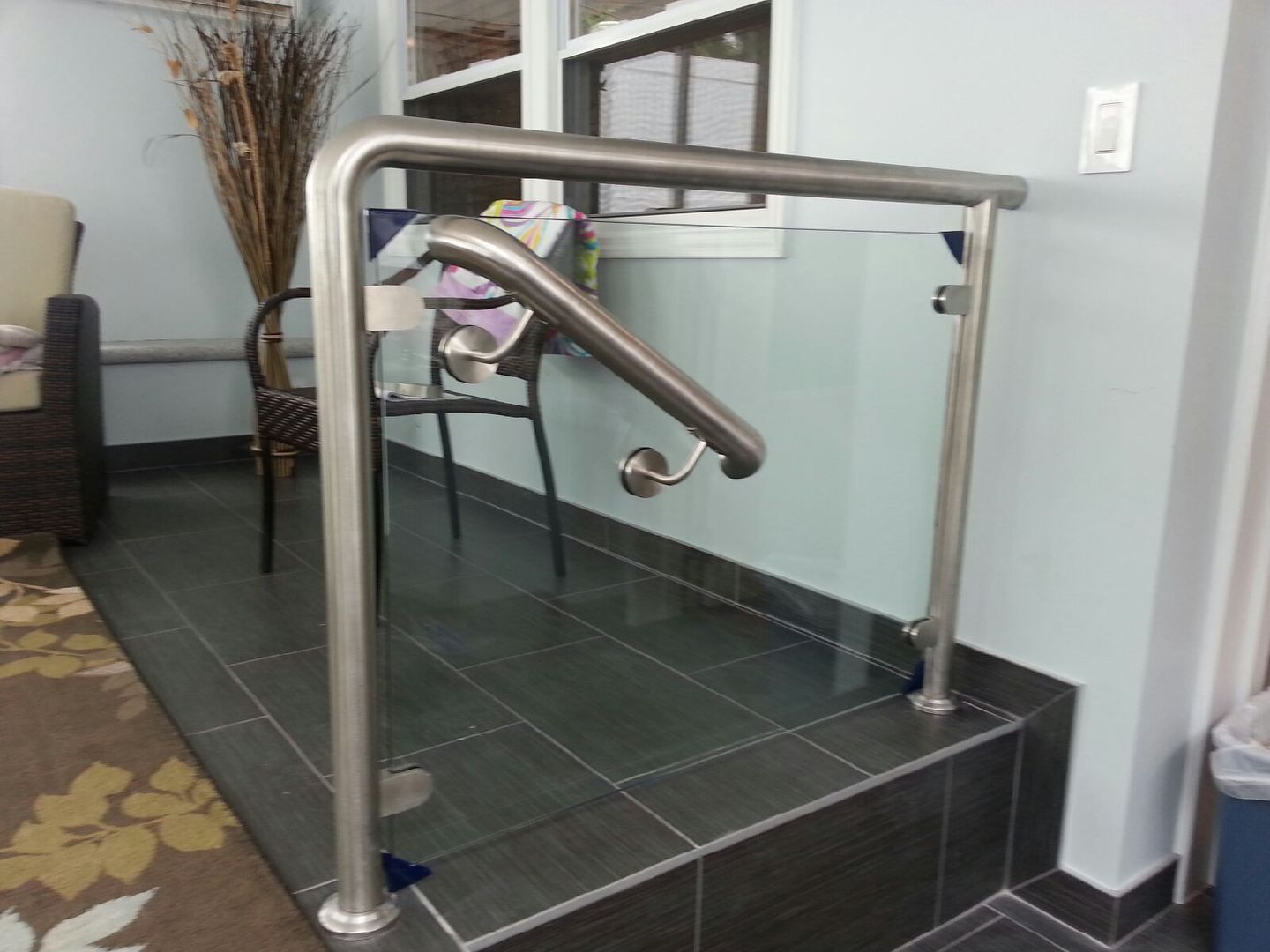 Indoor stairway with metal handrails and a curved grab bar beside tiled steps