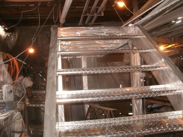 Metal HVAC ductwork and framing in a dimly lit construction or attic space.
