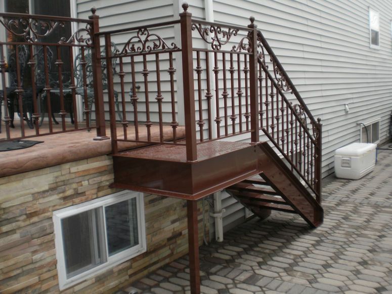 Backyard deck with metal railing, wooden stairs, and a basement window beneath the raised platform