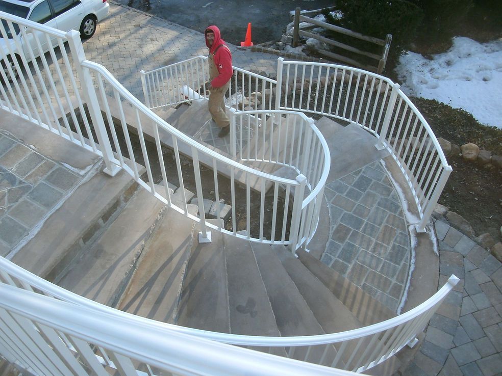 Curved outdoor staircase with white railings and a person in a red jacket near the top.