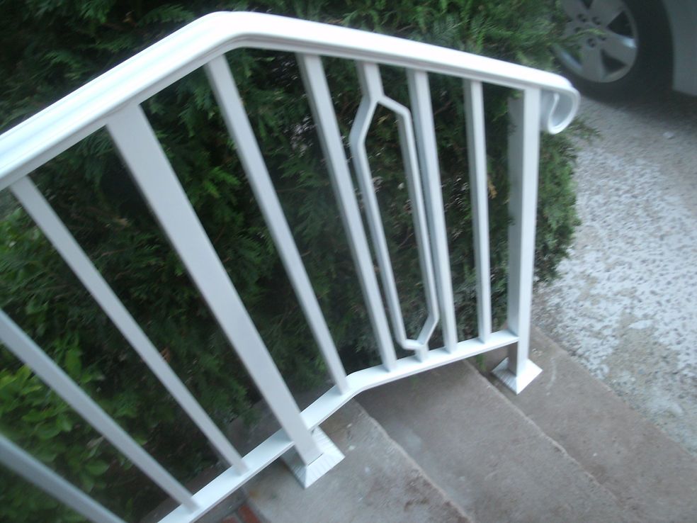 White metal stair railing beside concrete steps and a gravel path outdoors