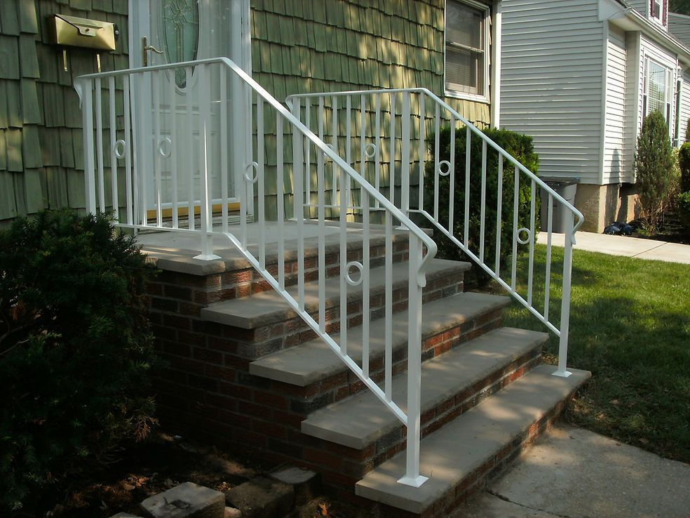 Front steps with white railings leading to a green house entryway
