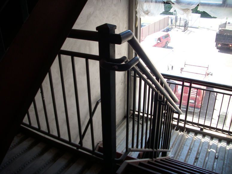 Stairwell with black metal railings overlooking a street and parked cars below