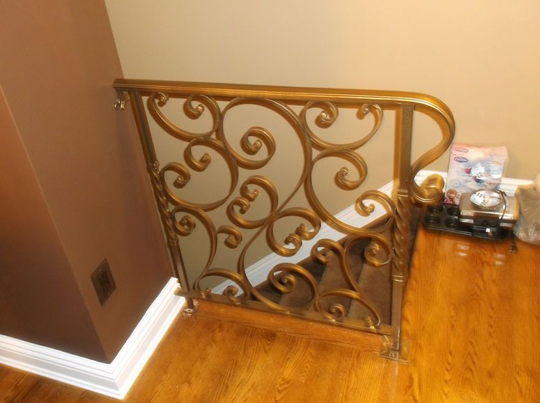 Decorative gold metal stair railing on hardwood floor in a hallway corner