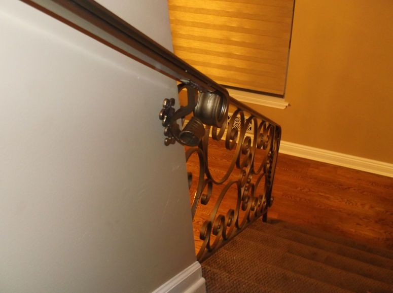 Wrought-iron stair railing beside a beige wall and hardwood floor in a home interior