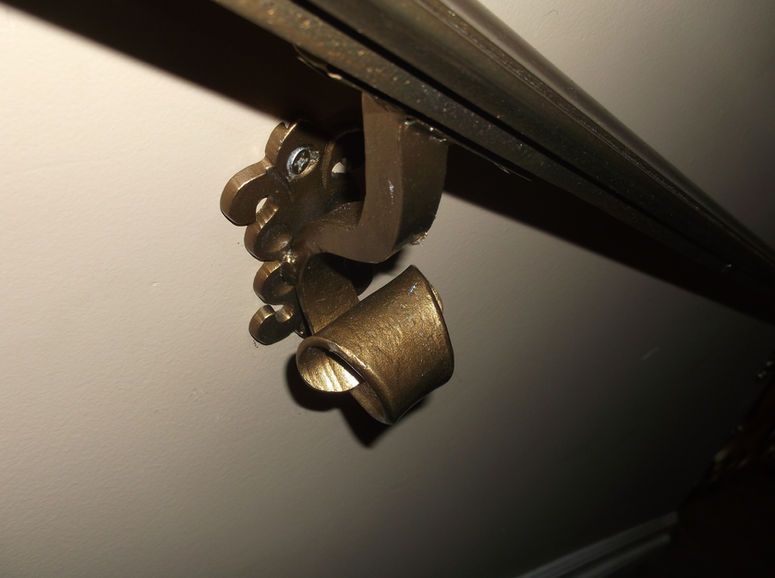 Close-up of a metal clamp attached to a black rail against a blurred gray background