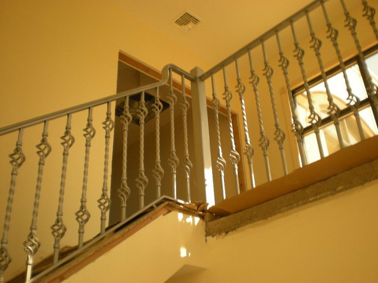 Indoor staircase with beige walls and ornate white railing, viewed from below.