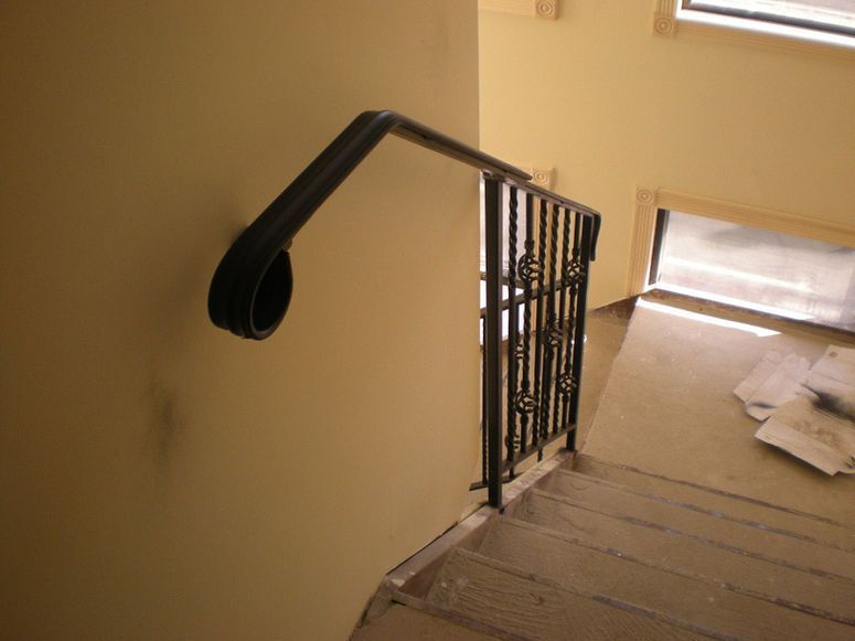 Stairwell with black handrail, carpeted steps, and a bright window landing below