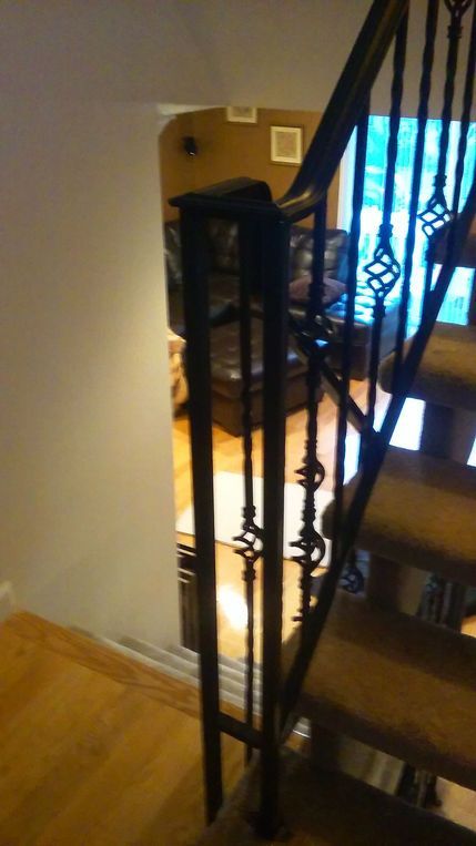 Indoor staircase with black metal railing beside a bright window and wooden floor.