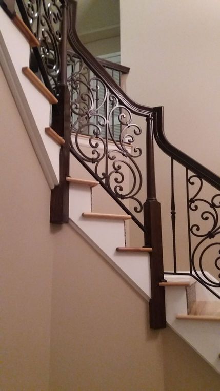 Ornate wrought-iron staircase railing along a beige interior staircase with white steps