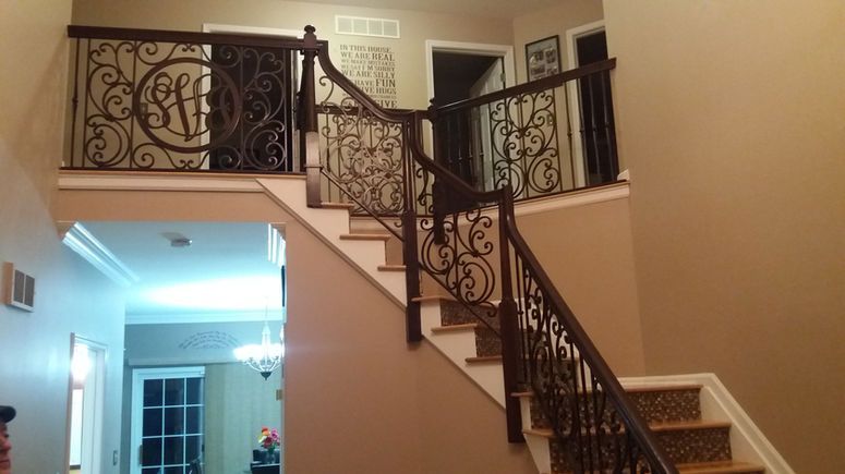 Interior staircase with ornate black wrought-iron railing and beige walls in a home foyer