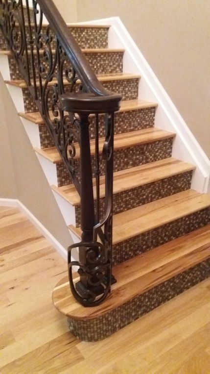 Carpeted staircase with a dark wooden railing and light wood floor at the bottom