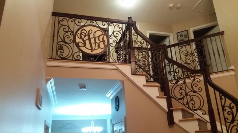 Decorative wrought-iron staircase railing in a warmly lit indoor foyer