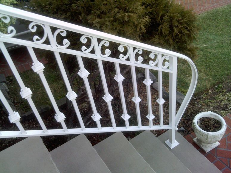 White wrought-iron stair railing beside outdoor steps and a brick planter