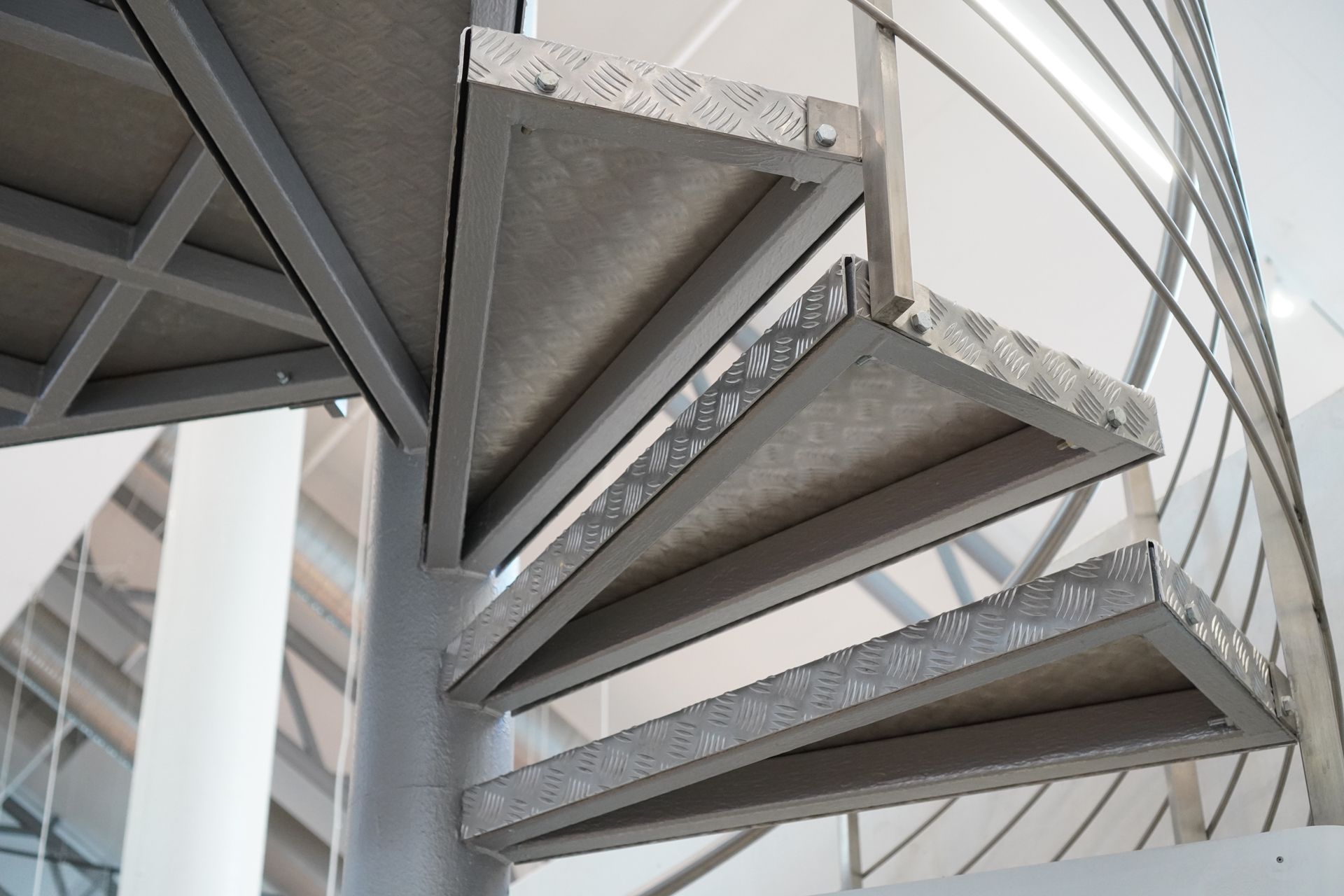 Concrete spiral staircase viewed from below, with metal railings and gray industrial structure