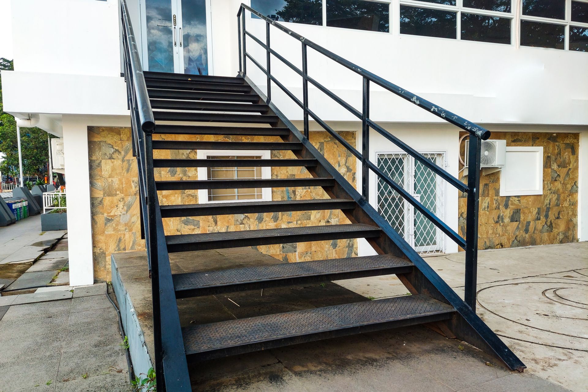 Outdoor concrete staircase with black railings leading to a building entrance