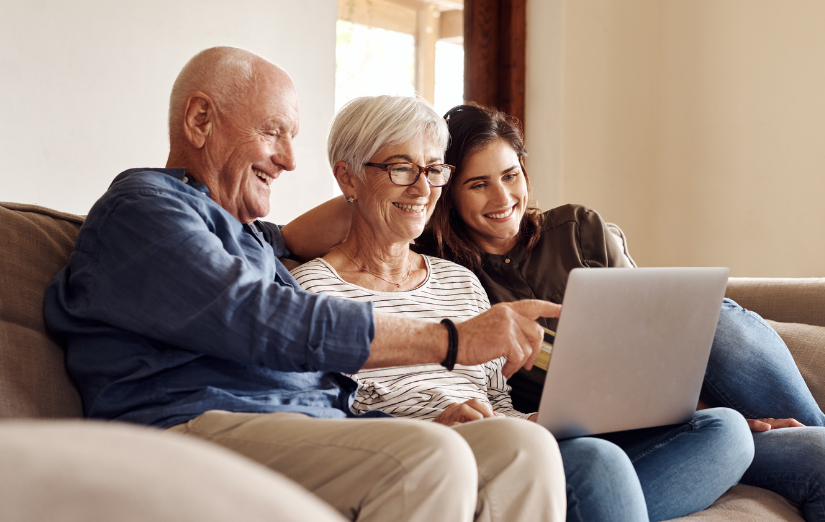 Three people sit on a couch looking at a laptop and smiling | mobile blood draw fl