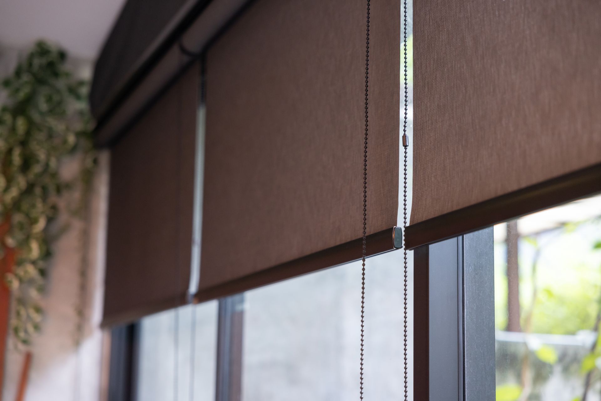 Three sun-blocking window treatments covering living room windows. 