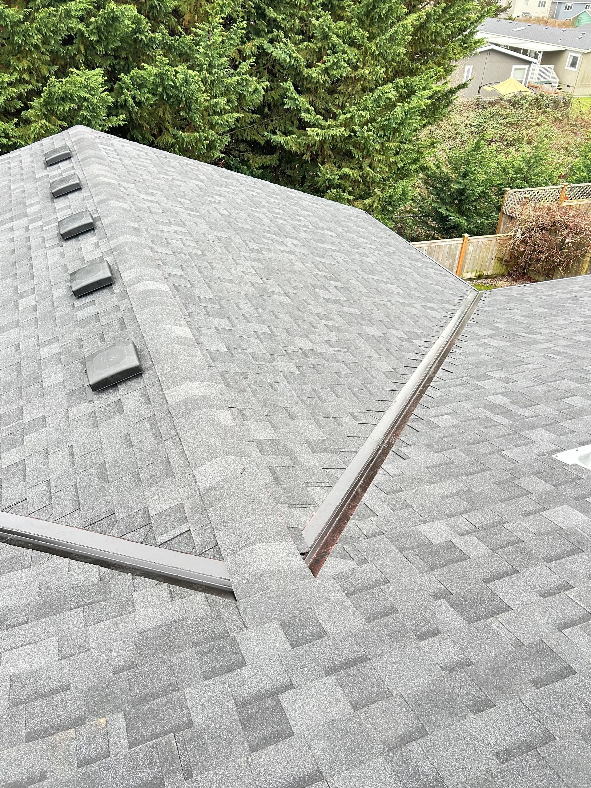 A roof is being installed on a house with mountains in the background.