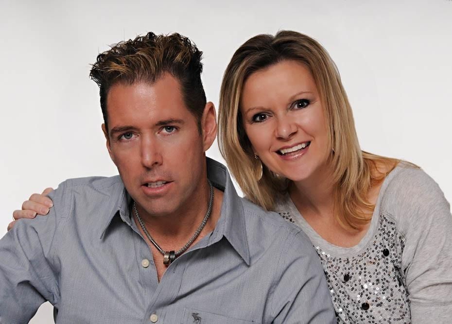 Two people posing closely together against a plain white background, both smiling softly.