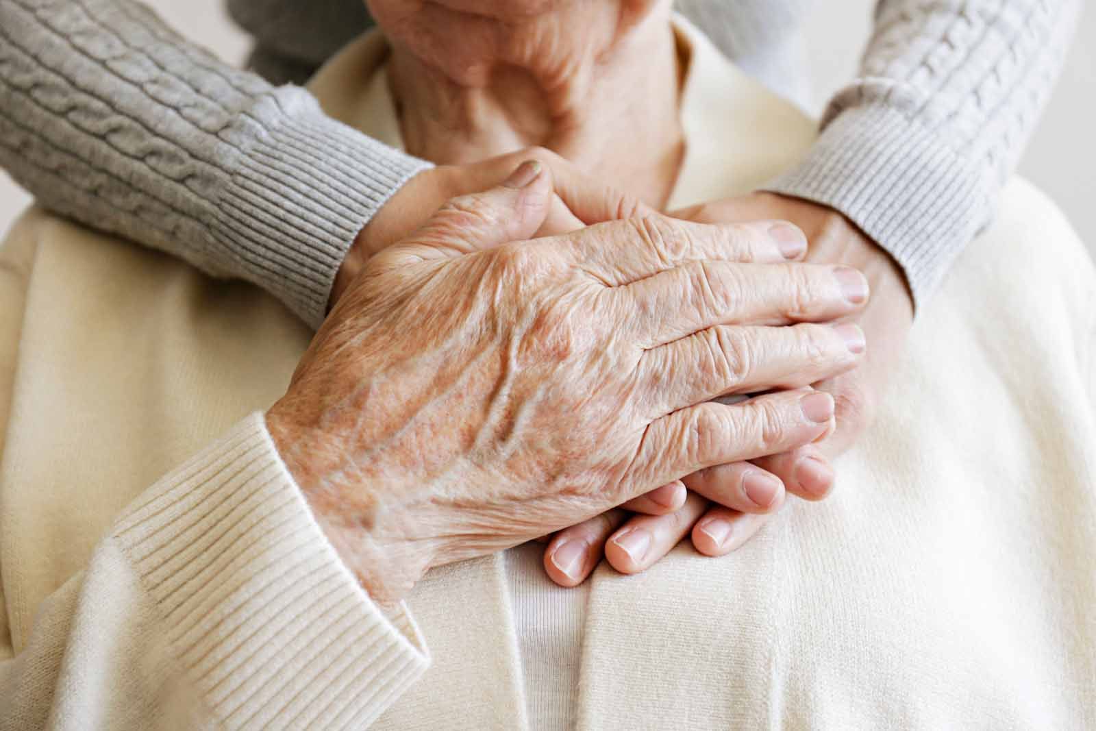 A woman is holding an older woman 's hand on her chest.