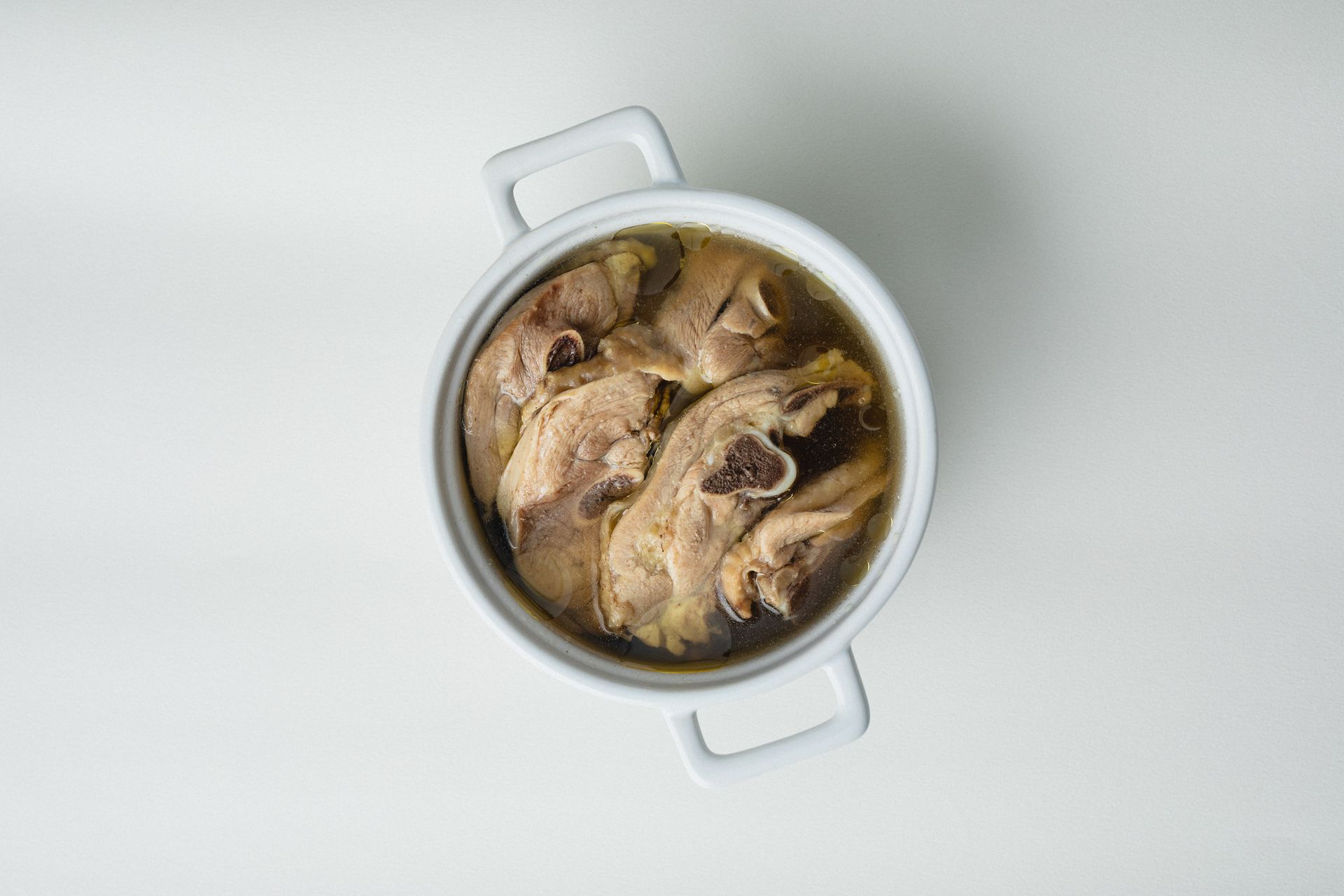 淺色背景上的白色鍋,盛滿熟肉,俯視圖