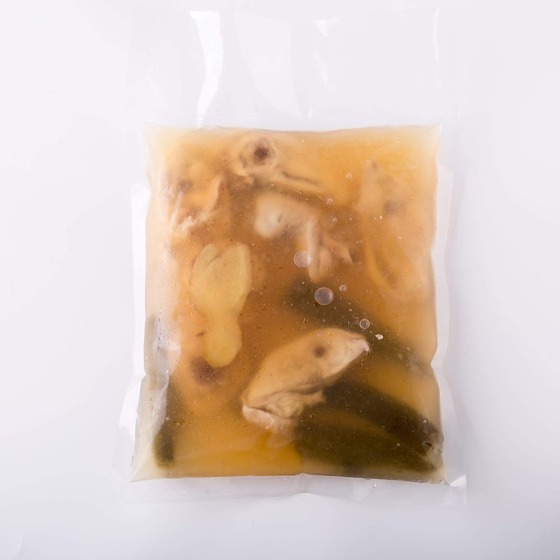 淺色背景上的白色鍋子裡盛著煮熟的肉、馬鈴薯和綠色蔬菜