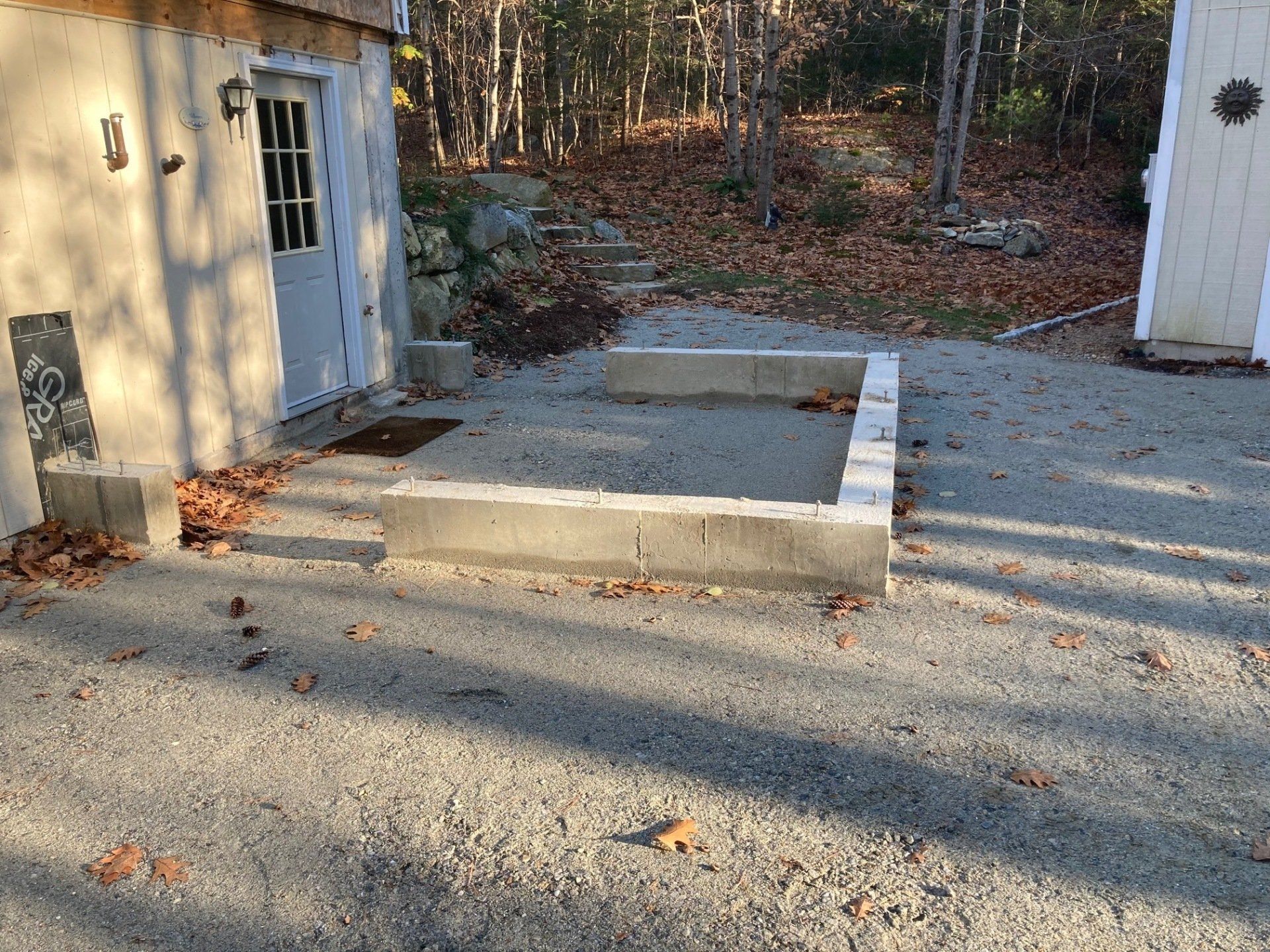 A concrete block is sitting in the middle of a gravel driveway in front of a house.