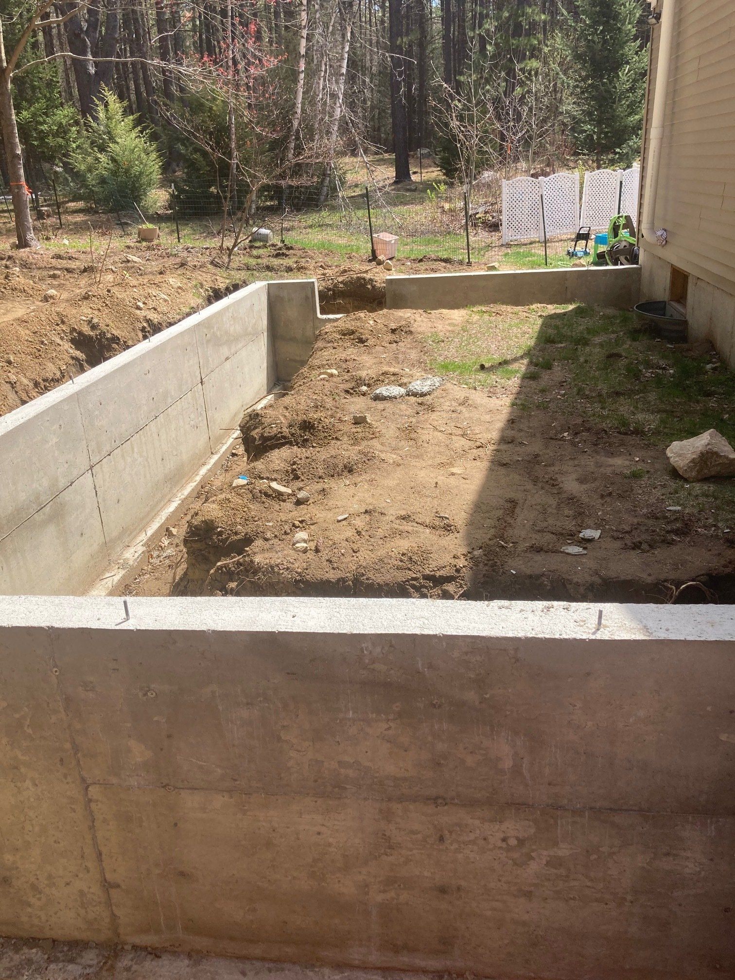 A concrete wall is being built in the backyard of a house.