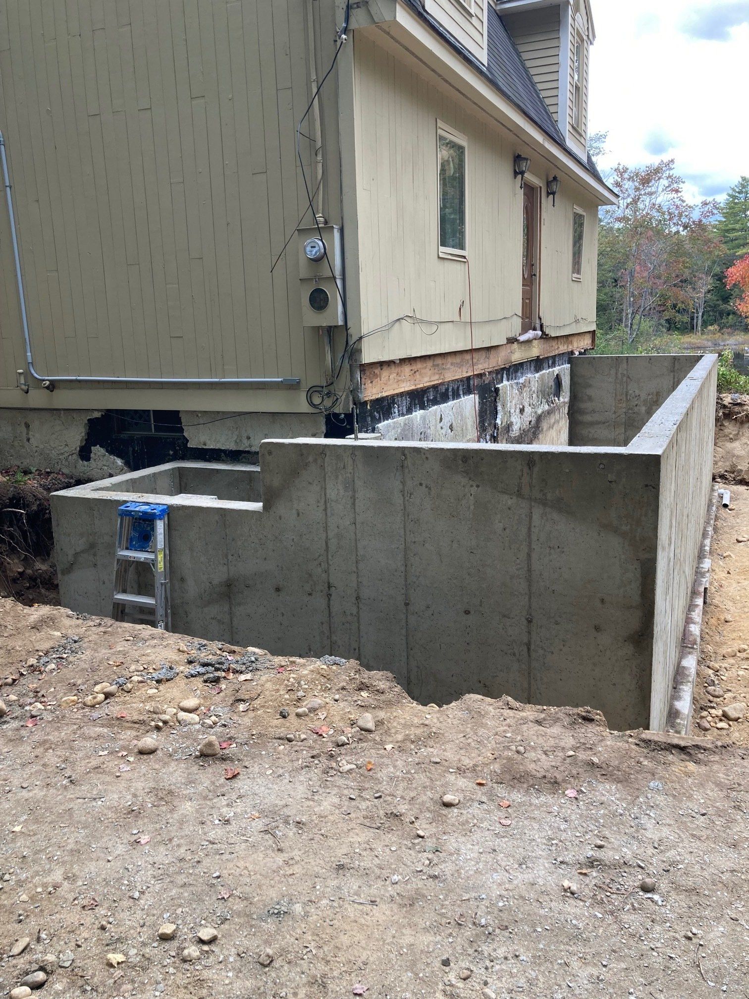 A concrete wall is being built in front of a house.