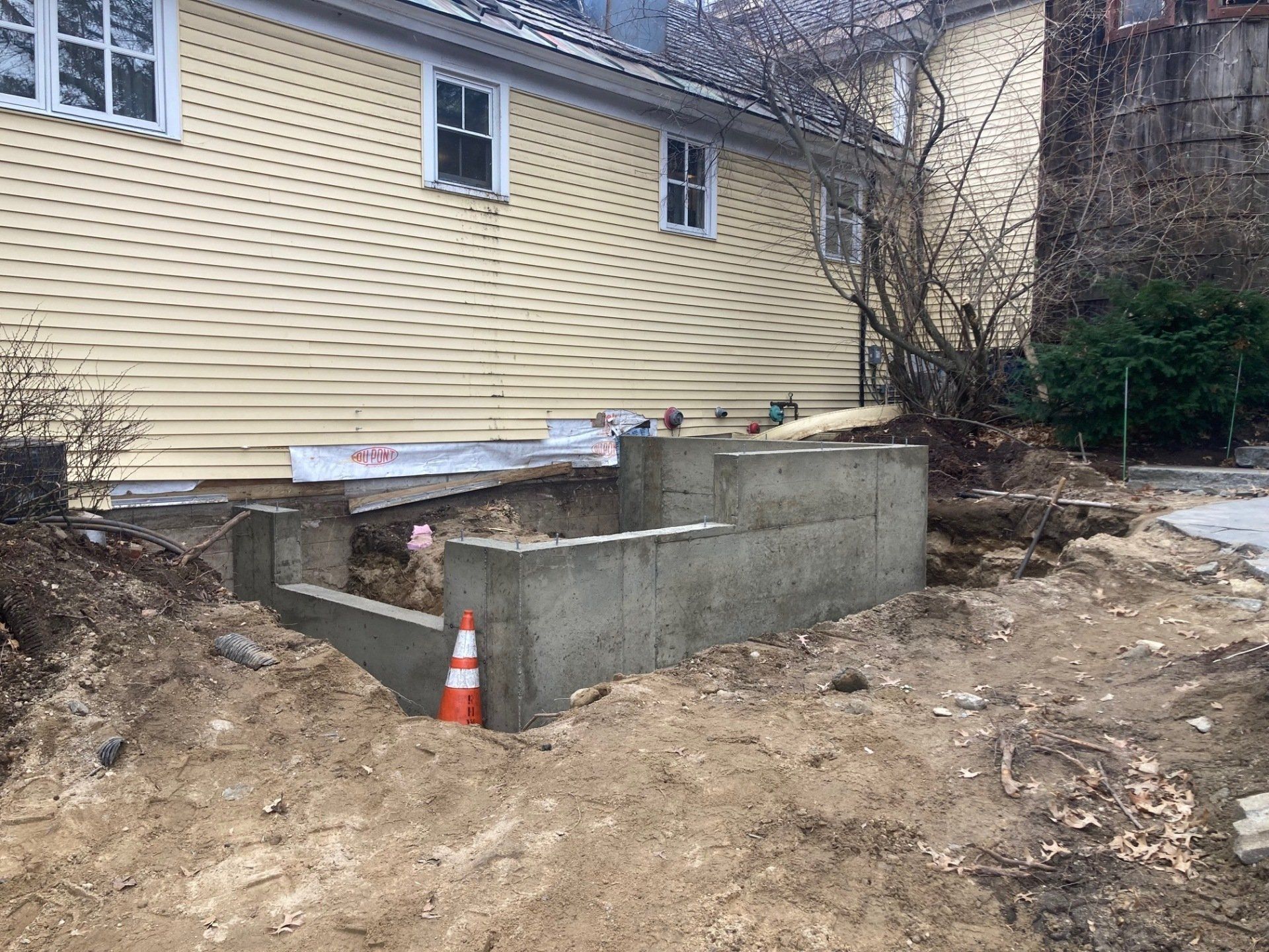 A yellow house with a concrete foundation in front of it.