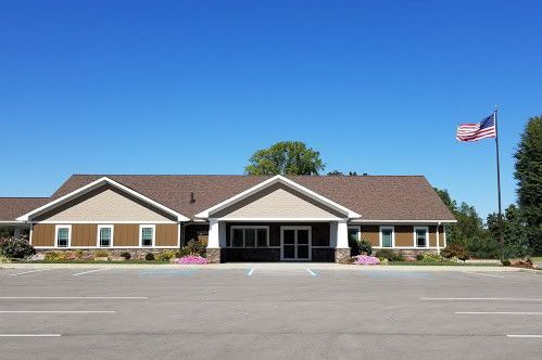 A single-story building with a brown roof and a US flag. Clear blue sky.