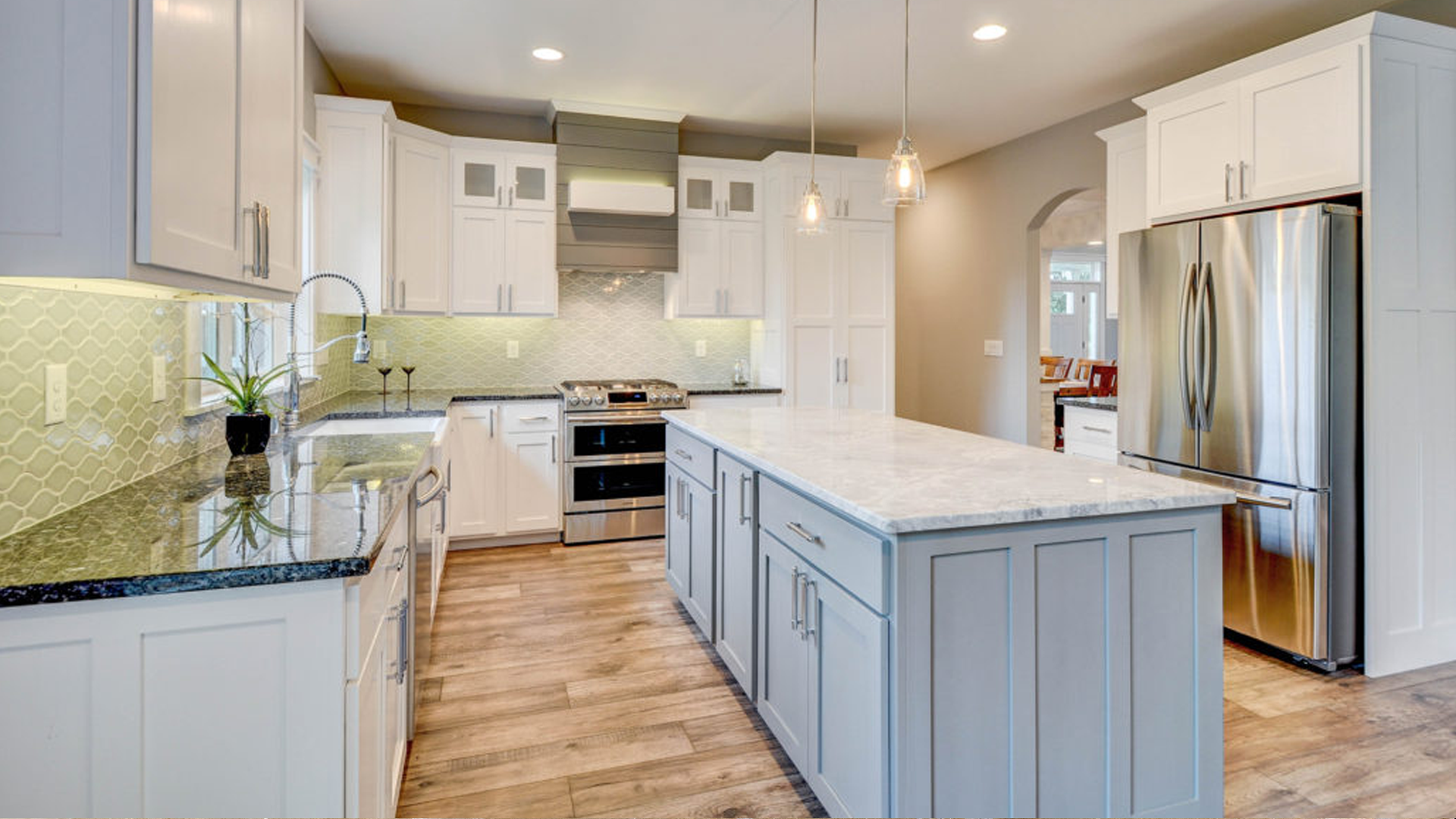 Modern kitchen with white and gray cabinets, stainless steel appliances, and a central island.