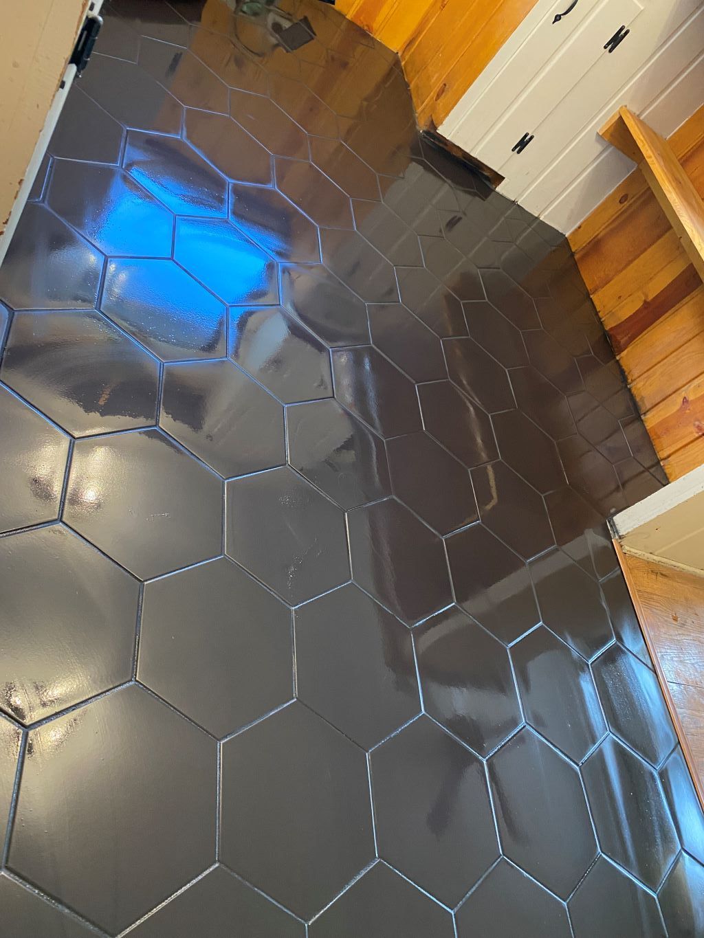 Dark gray hexagonal tile floor in a room, reflecting light.